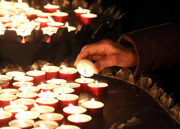 istock elderly woman in prayer and lit a candle 464681738