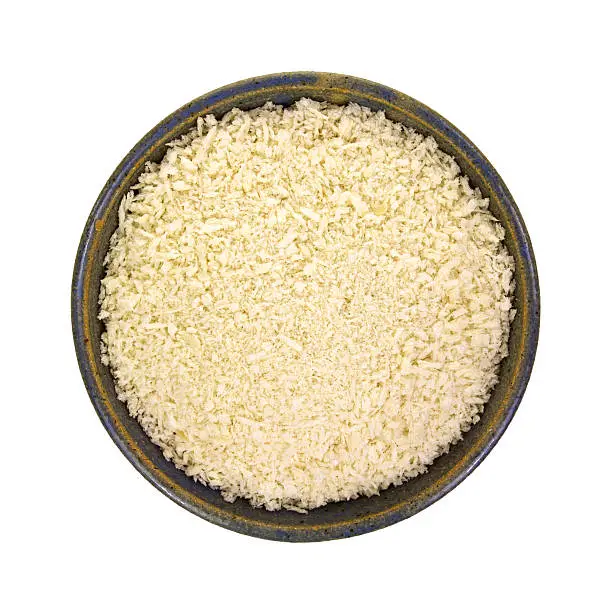 Top view of a bowl filled with panko style flaked bread crumbs on a white background.