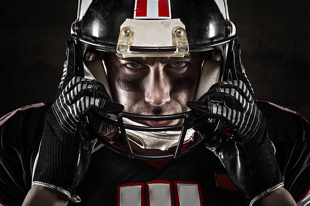 Portrait of American football player in jersey and helmet Portrait of american football player looking at camera with intense gaze safety american football player stock pictures, royalty-free photos & images