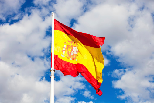 Flag of Spain over blue sky moving in wind
