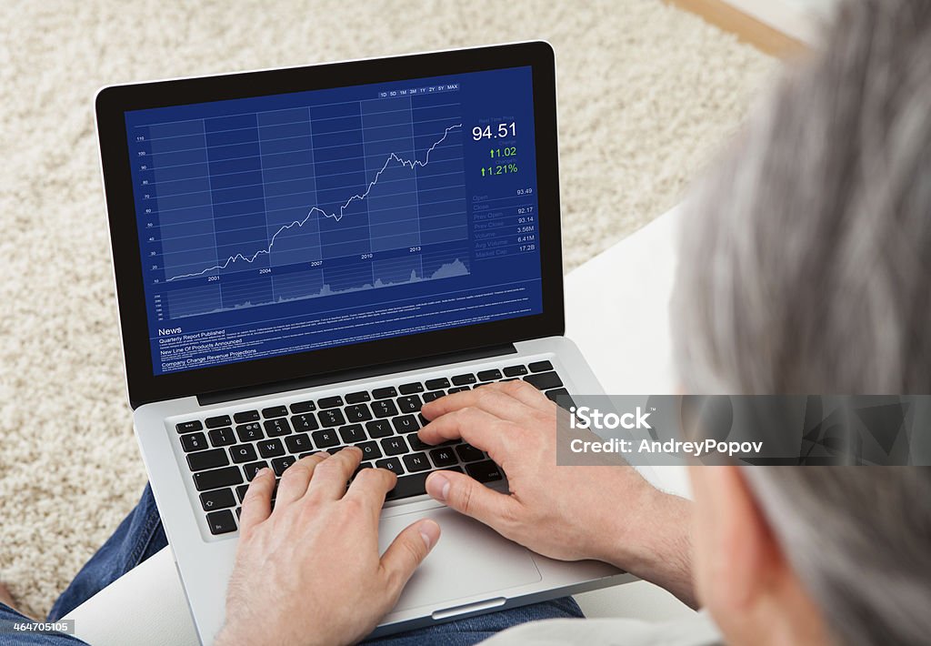 Mature man using laptop Close-up of mature man looking at stock charts Stock Market and Exchange Stock Photo