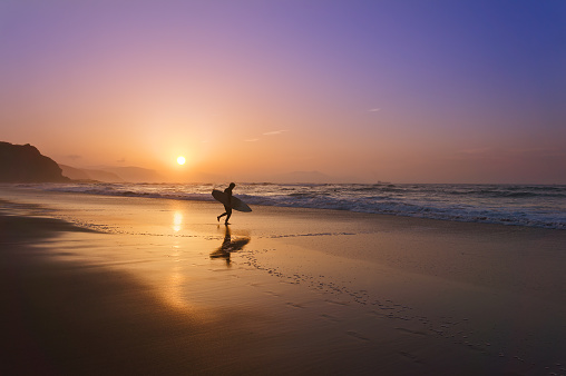 surfer entering water at the sunset