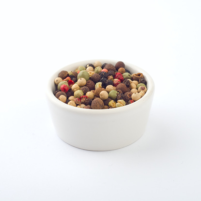 Peppercorns in a white bowl.
