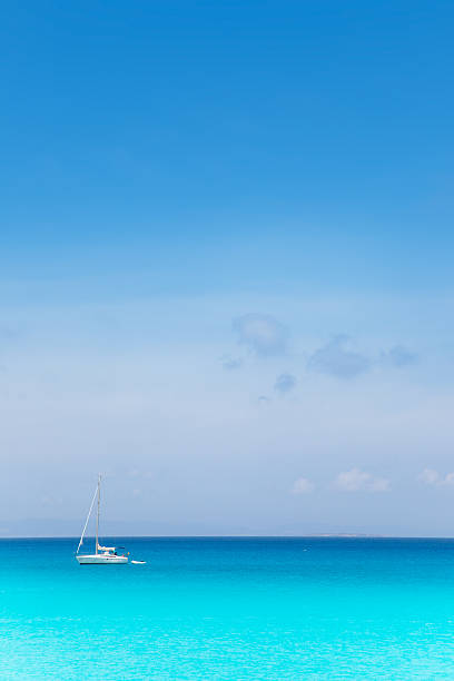 Balearic mediterranean turquoise sea with sailboat under blue sky