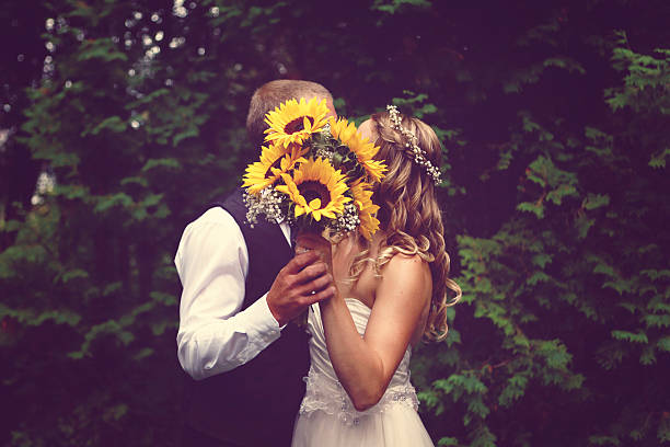 Bride and Groom Kissing Behind Bouquet stock photo