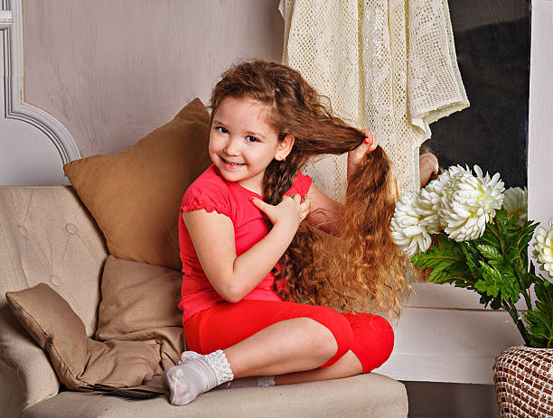Portrait of a little girl with long curly hair brushing her hair