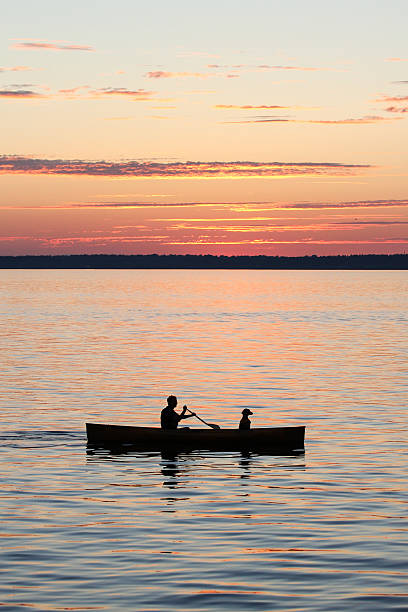 istock Man and dog in Canoe on the bay at sunset 464729244