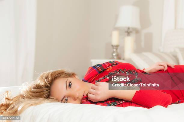Pretty Blonde Girl In Red Laying On Bed Lamp Background Stock Photo - Download Image Now