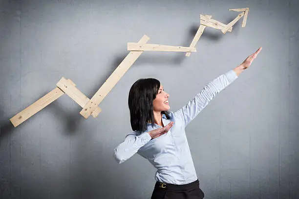 Photo of Excited businesswoman in front of pointing up business chart.