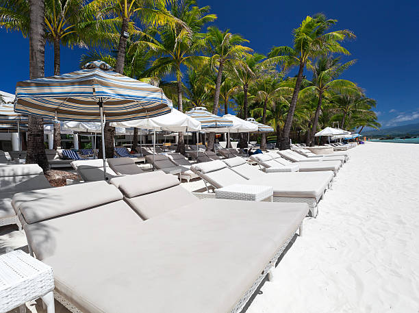 istock Sun umbrellas and beach beds on tropical coastline 464741242