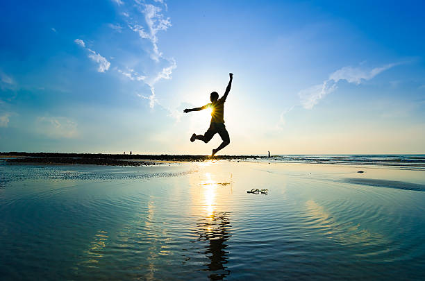 istock A man jumping over the water while the sun rises 464753668