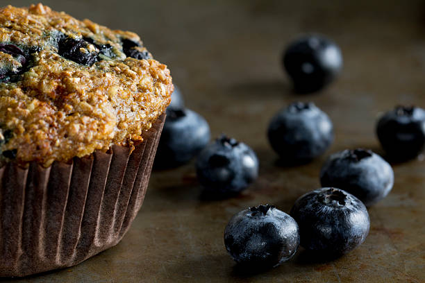 plano aproximado de mirtilo com espalhados mirtilos muffin de farelo - muffin blueberry muffin healthy eating bran muffin imagens e fotografias de stock