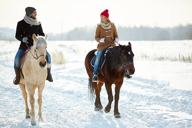 istock Joyous couple horseback riding along snowy trail 464761620
