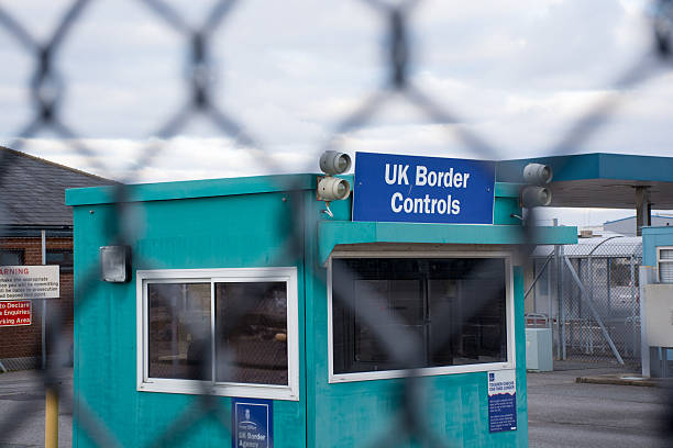 UK Border control checkpoint immigration election Poole, UK - January 31, 2015: Poole, UK, Immigration is a hot topic in the UK, the picture shows border controls in the port of Poole. The picture is taken through a wirefence giving the impression of being on the other side of the border. poole harbour stock pictures, royalty-free photos & images