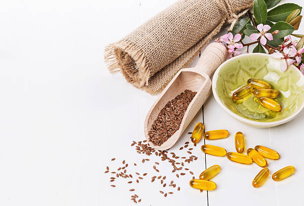 Linseed and flaxseed oil capsules over white background stock photo