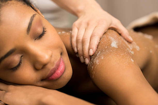Body exfoliation Spa therapist applying massage salt on young woman back at spa exfoliating scrub stock pictures, royalty-free photos & images