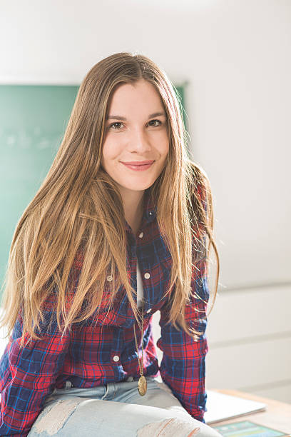 istock Young girl sitting on table in class room 464768940