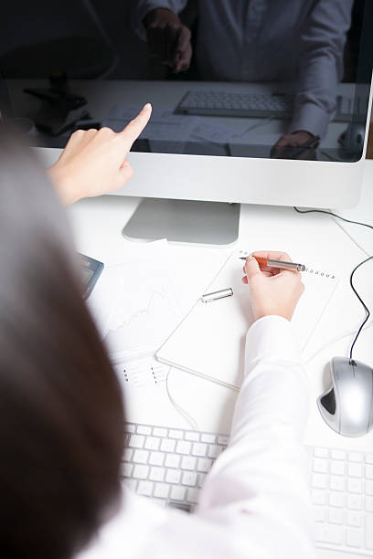 istock Woman working at desk, pointing on screen 464769054
