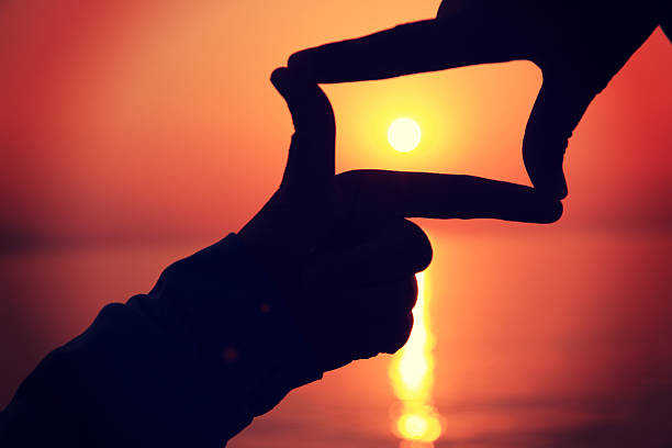 istock hands make a heart shape against sunset at seaside 464775520