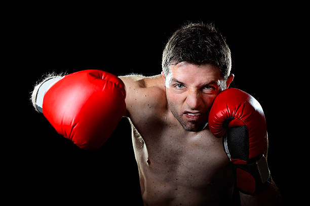 istock man boxing in fighting gloves throwing angry right hook punch 464775908