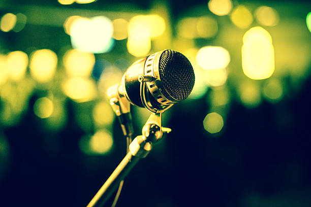 istock Microphone on stage against yellow, green background 464780006