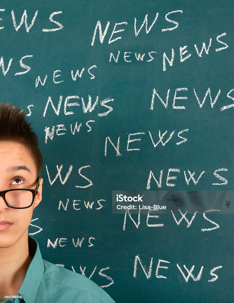 News Pensive young man with his back against a green blackboard. He is wearing glasses and looking up towards multiple words. The chalkboard shows multiple words outlined in white. The word is 'News' and symbolises 'The Media' concept.  20-29 Years Stock Photo