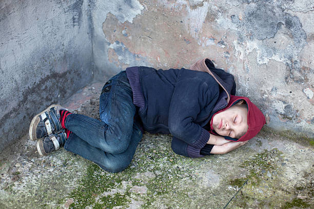 istock homeless boy sleeps under the wall 464791273