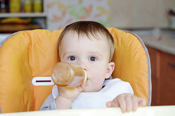 istock baby age of 1 year drinks from small bottle 464792607