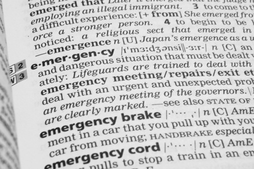 Closeup shot of the word EMERGENCY in a dictionary. Page is in a slight angle. Focus is on the word emergency.