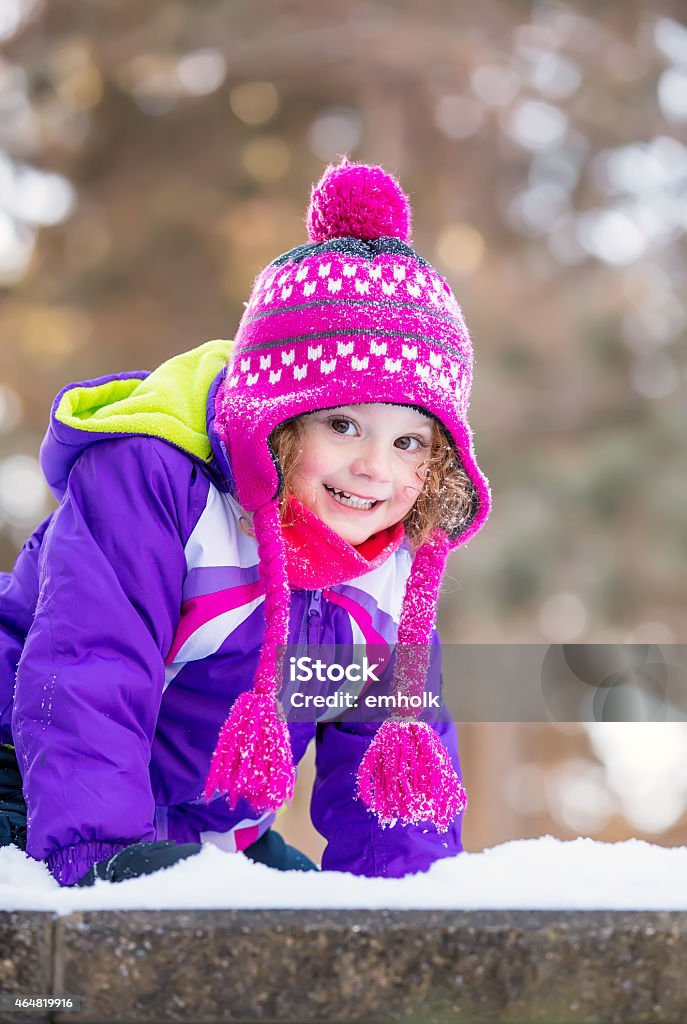 Girl in Purple Jacket Smiling in the Snow Cute little girl smiling at the camera while playing in the snow. Child Stock Photo