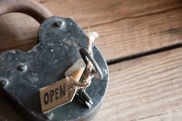 label open, old padlock and key on wooden plank