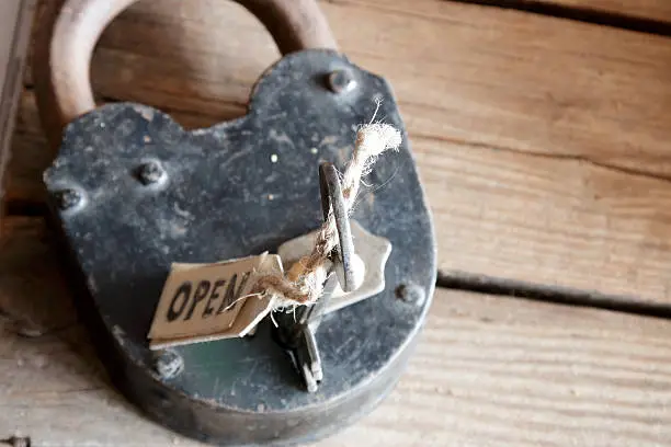 label open, old padlock and key on wooden plank