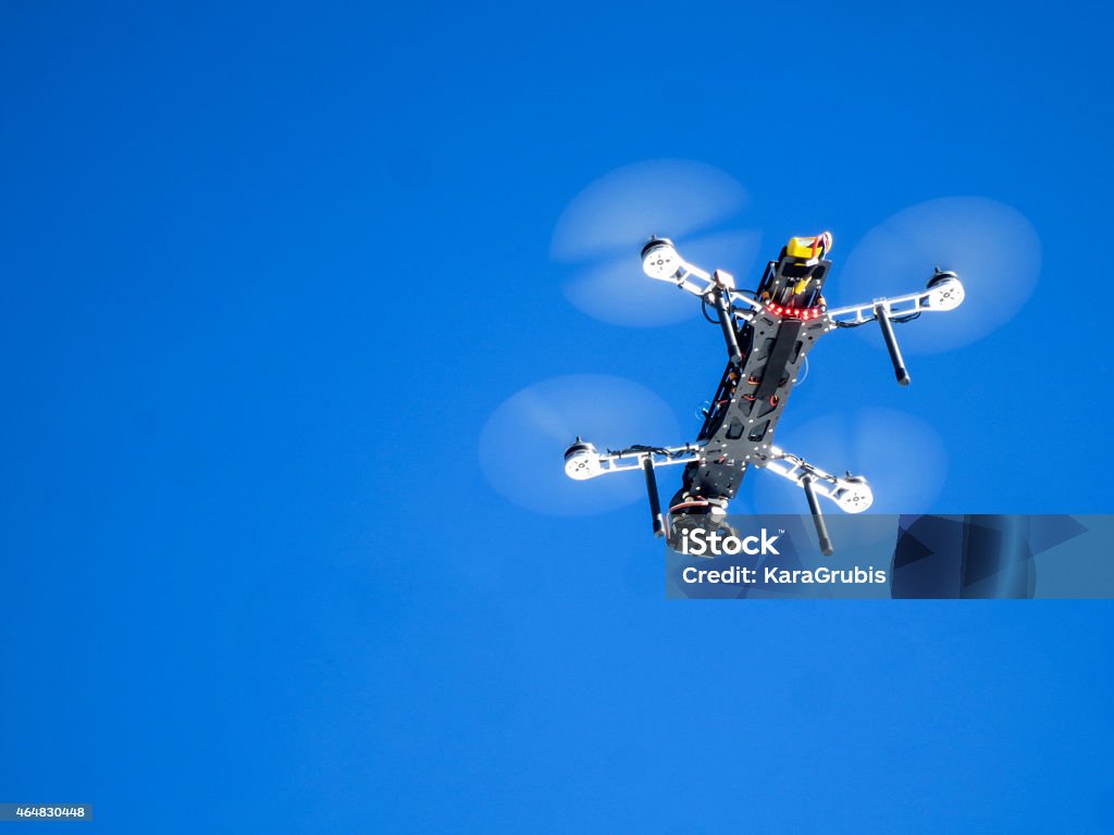 Drone with camera against blue sky UAV or drone flying through a clear, blue sky to video the start of a race. 2015 Stock Photo