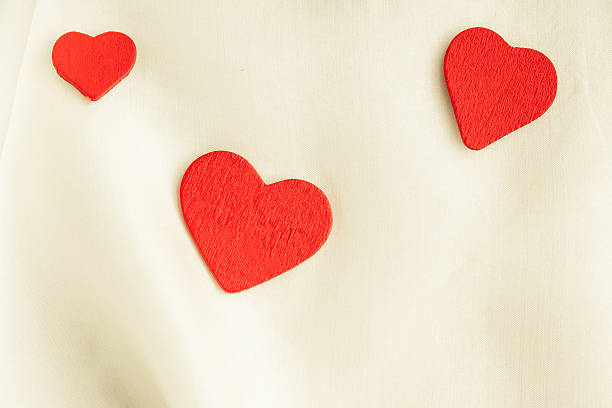 istock Red wooden decorative hearts on white silk background. 464831253