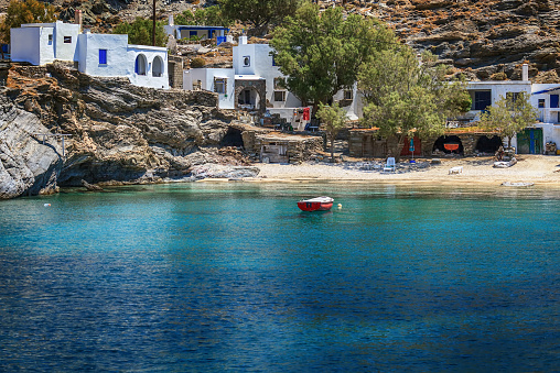 Small village of Mali, in Tinos island, Greece, with clear transparent waters and a fishing boat.