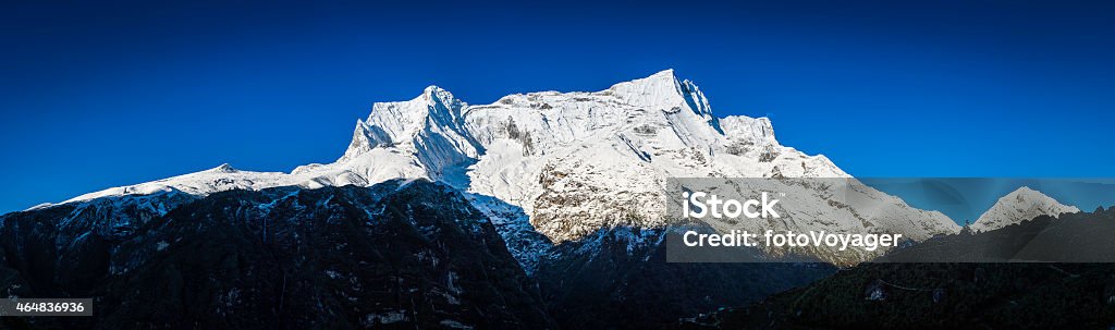 Himalaya mountains snowy peaks panorama high above Namche Bazaar Nepal Snow capped Himalaya mountain peaks above the traditional teahouses and prayer flags of Namche Bazaar, the iconic Sherpa village and trading post deep in the Sagarmatha National Park, a UNESCO World Heritage Site, Nepal. ProPhoto RGB profile for maximum color fidelity and gamut. 2015 Stock Photo