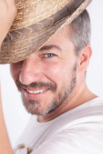 smiling cacasian man with a beard lifting a hat