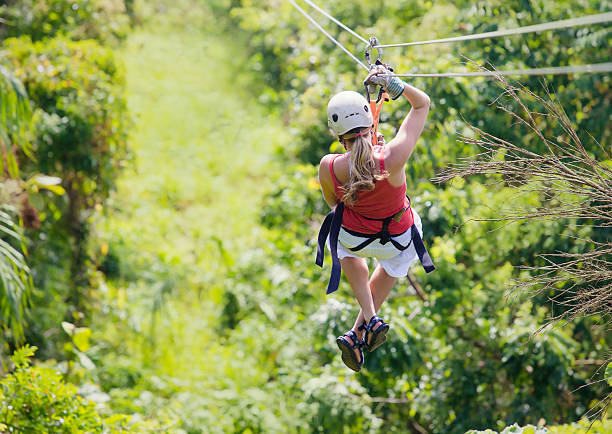 Woman going on a jungle zipline adventure Woman enjoying a fun zip line tour in the jungle while on vacation canopy tour photos stock pictures, royalty-free photos & images