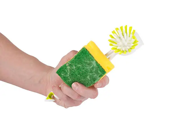 A caucasian hand is holding a yellow green  sponge and a brush in his hand. Isolated on white.