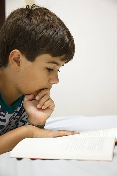 istock Child reading book lying in bed . 464841474