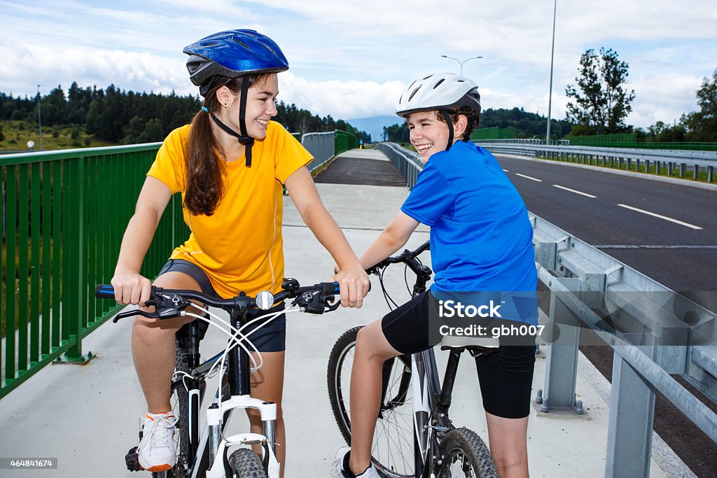 Urban biking- girl and boy riding bikes in city Active young people riding bikes  14-15 Years Stock Photo