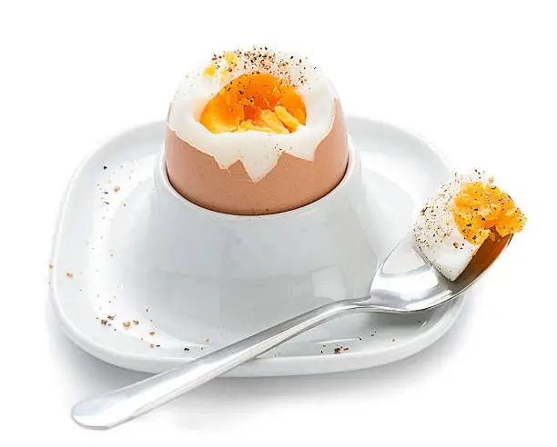 Soft boiled egg in eggcup over white background. 