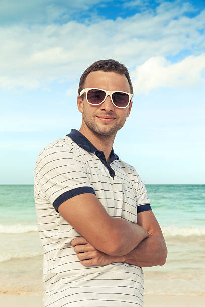 istock Caucasian man standing with sunglasses on sea coast 464849608