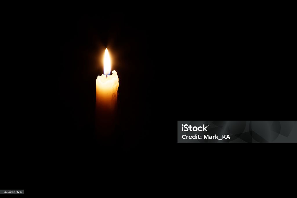 Glowing candle in the dark The glowing candle's image is isolated against a black background and fades into a shadow. 2015 Stock Photo