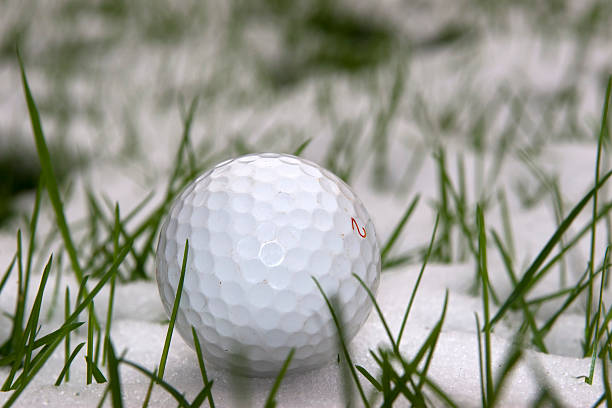 lone single golf ball in the snow stock photo