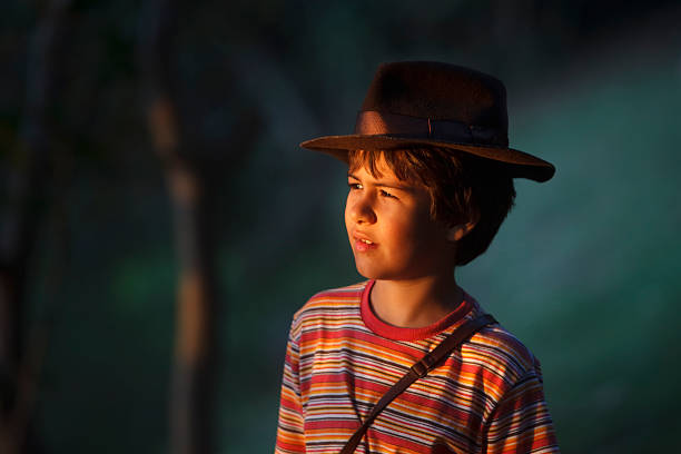 Boy taking adventurer hat watching the scenery .