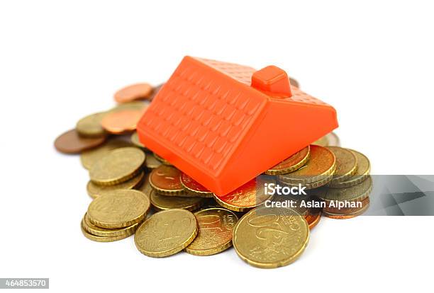 A Pile Of Gold Coins With A Toy House Roof On Top Stock Photo - Download Image Now - 2015, Architecture, Bank Account