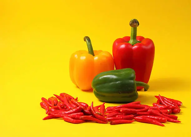 red chili peppers and colored paprikas against a yellow background