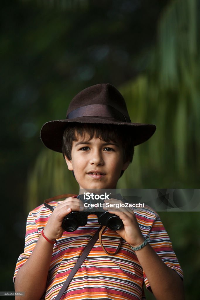 Boy with adventurer hat watching with binoculars . Child Stock Photo