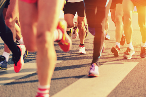 happy smiling man running marathon showing victory sign with fingers